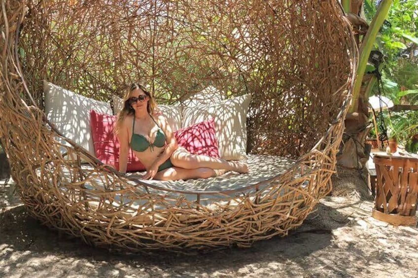 A person sitting in a woven hanging chair outdoors. 1