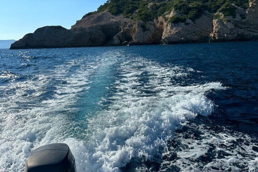 A boat moving through a coastal area with rocky cliffs and clear blue water. 5