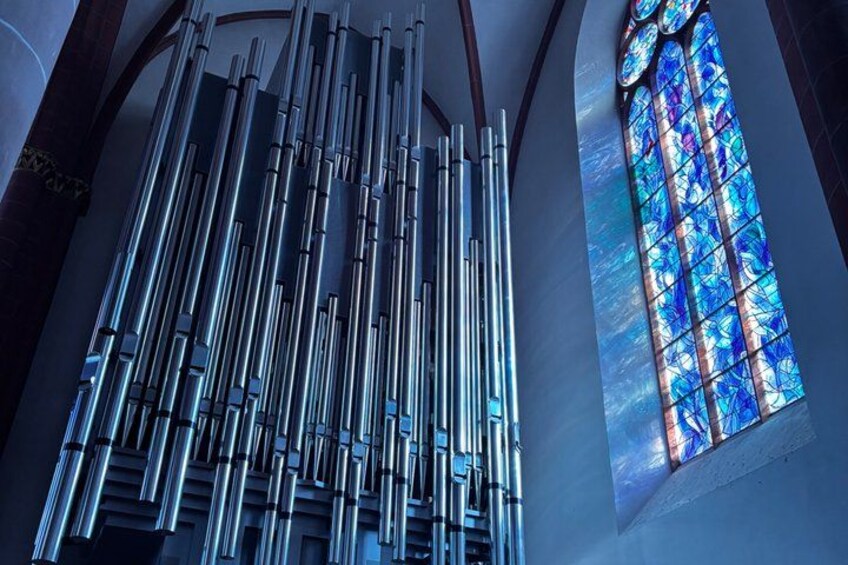A church interior with a large pipe organ and stained glass window. 2