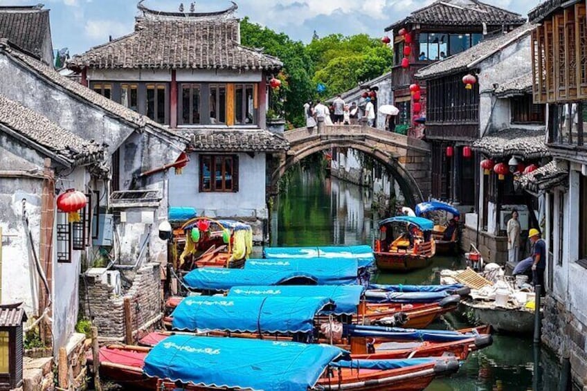 Een traditionele Chinese watertoren met smalle kanalen, houten bootjes en gebouwen met pannendaken. 1