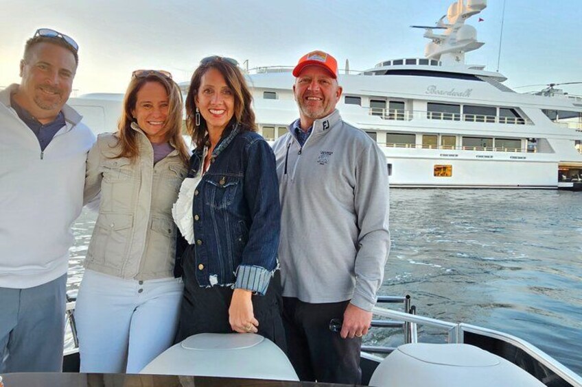 A group of people on a boat with a large yacht in the background. 1