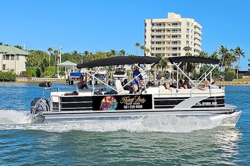 A speedboat with passengers, moving on water with a building and palm trees in the background. 4
