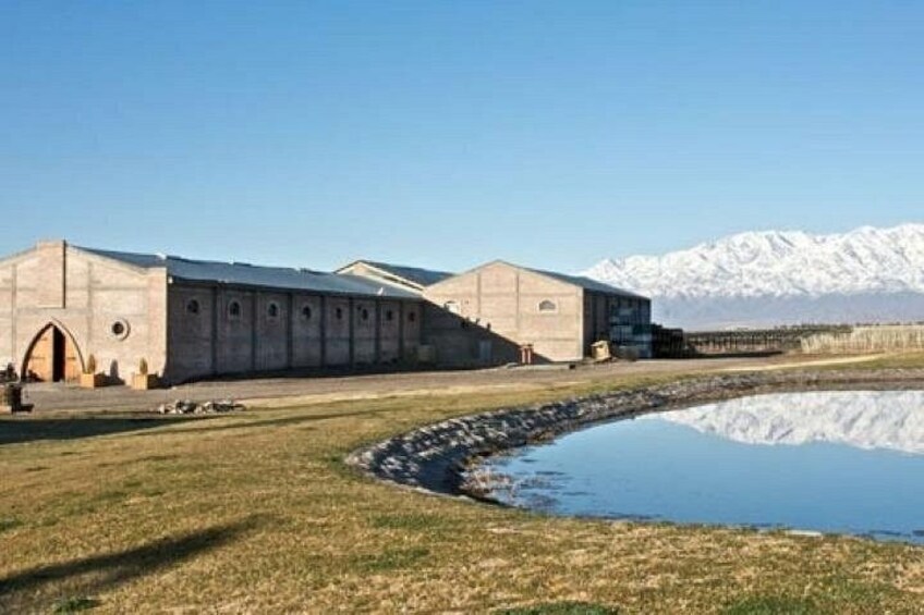 Ein großes Gebäude mit einem spiegelnden Pool, schneebedeckten Bergen im Hintergrund und einem klaren Himmel. 2