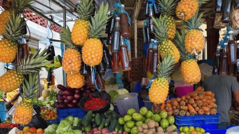 A market stall with various fruits and vegetables, including pineapples, bananas, and carrots. 1