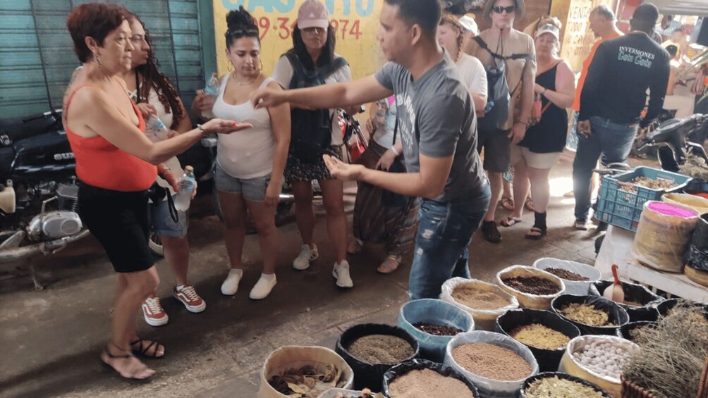 A group of people at a market stall with various bags of grains and seeds. 4