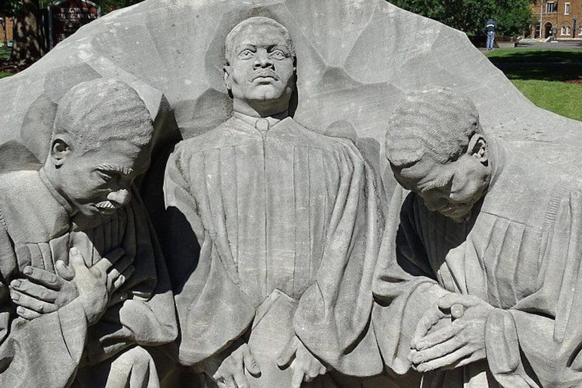 A stone sculpture of three figures in prayer. 4