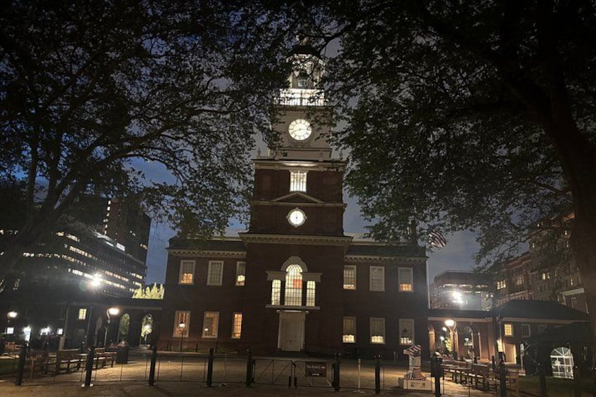 Een historisch gebouw met een klokkentoren, omringd door bomen en verlicht door lantaarns. 3
