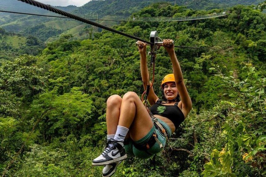 En person som åker på en zipline genom en frodig, grön skog. 4