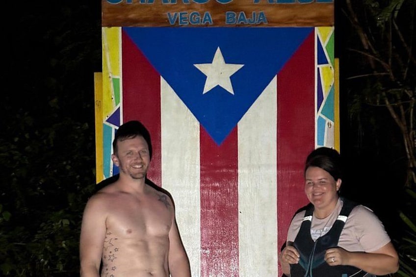 A man and a woman standing in front of a colorful sign with a star and stripes. 3