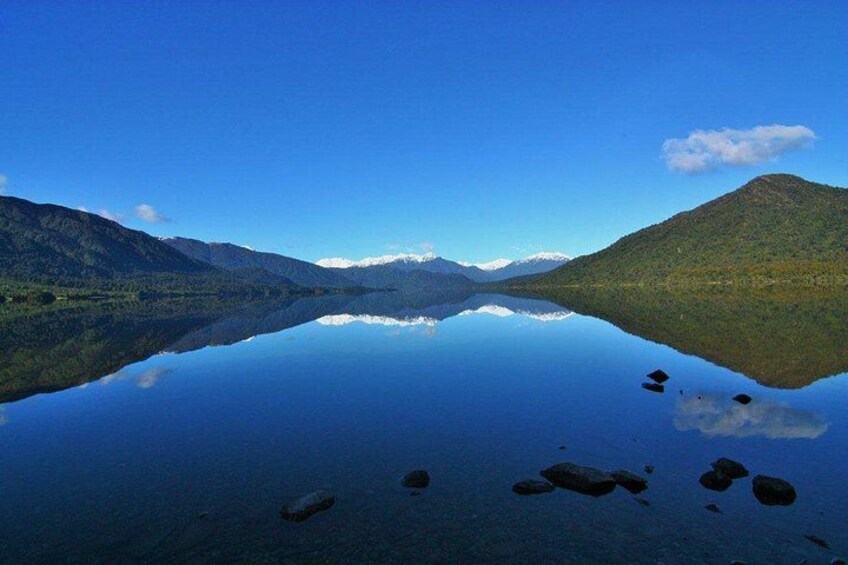 A calm lake with mountains in the background and a clear blue sky. 4