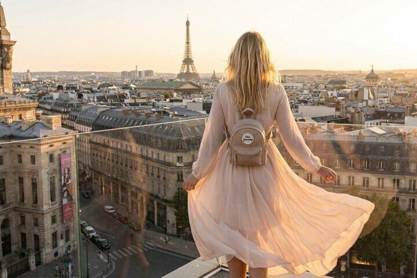 A person in a flowing dress standing on a balcony overlooking a cityscape with the Eiffel Tower in the distance. 5