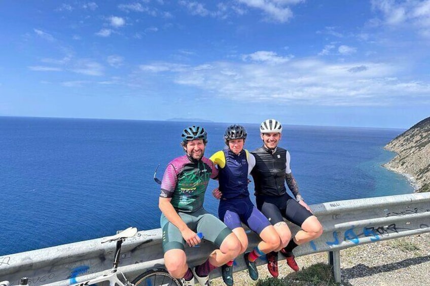 Three cyclists sitting on a railing by the sea. 1