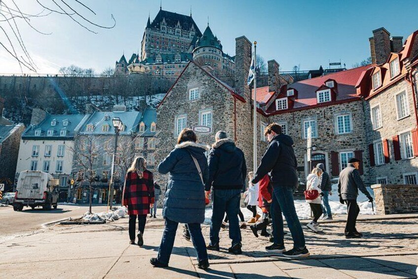 A group of people walking on a city street with historic buildings and a castle in the background. 3