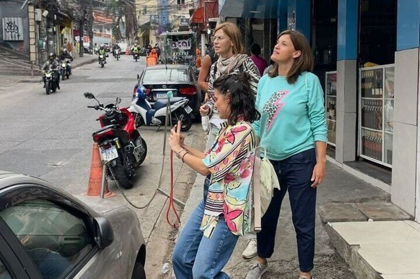 Une scène de rue avec une femme prenant une photo, une moto garée et une voiture. 2