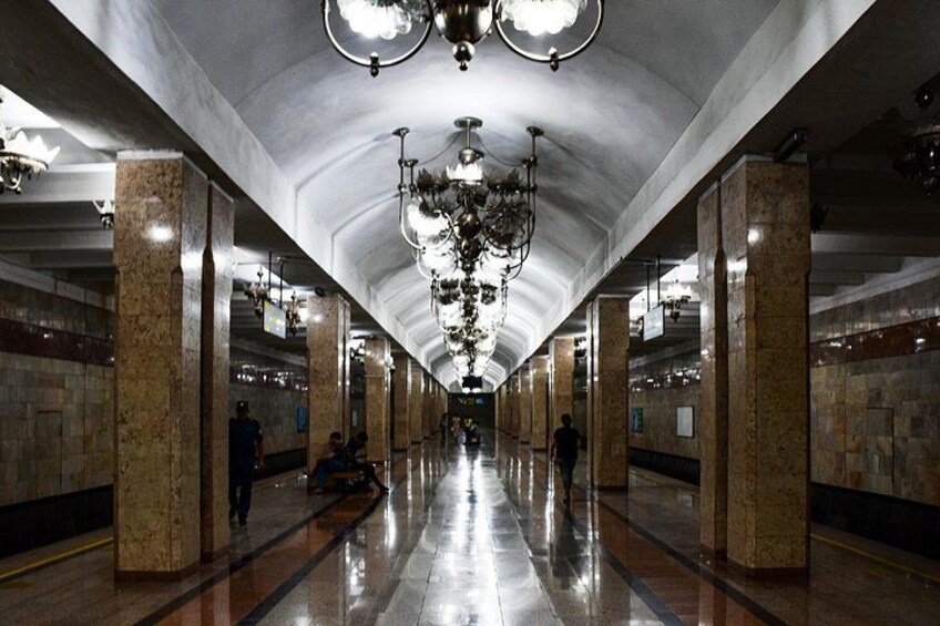 A subway station with marble columns, chandeliers, and a polished floor. 3