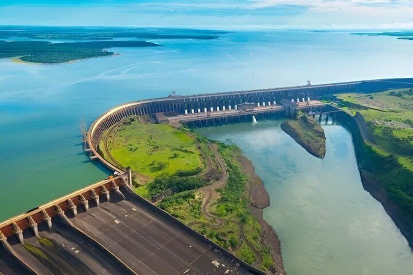 A large dam with a curved spillway, a bridge, and a river. 1