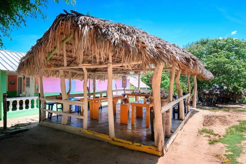 A thatched-roof gazebo with wooden pillars, surrounded by a concrete floor and a metal railing. 4