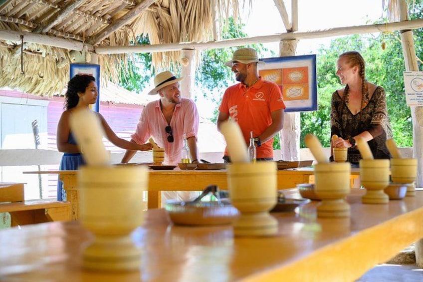 A group of people playing a board game with wooden pieces on a table under a thatched roof. 5