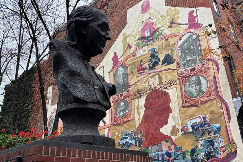 A statue of a person with a mural in the background. 1