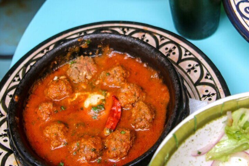 A bowl of meatballs in tomato sauce with a red chili pepper. 5