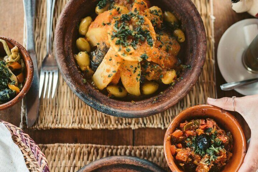 A rustic dining table with a variety of dishes, including a stew with potatoes and beans, a bowl of vegetables, and a small dish of meat. 3