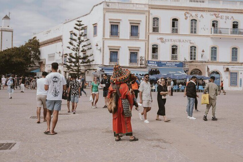 A busy public square with people walking and standing. 1