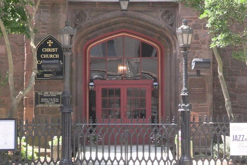 A church entrance with a red door, a signboard, and a metal fence. 5