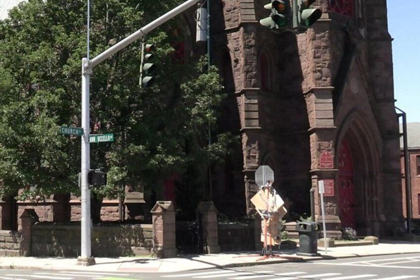 A church with a large steeple, a street sign, and a traffic light. 2