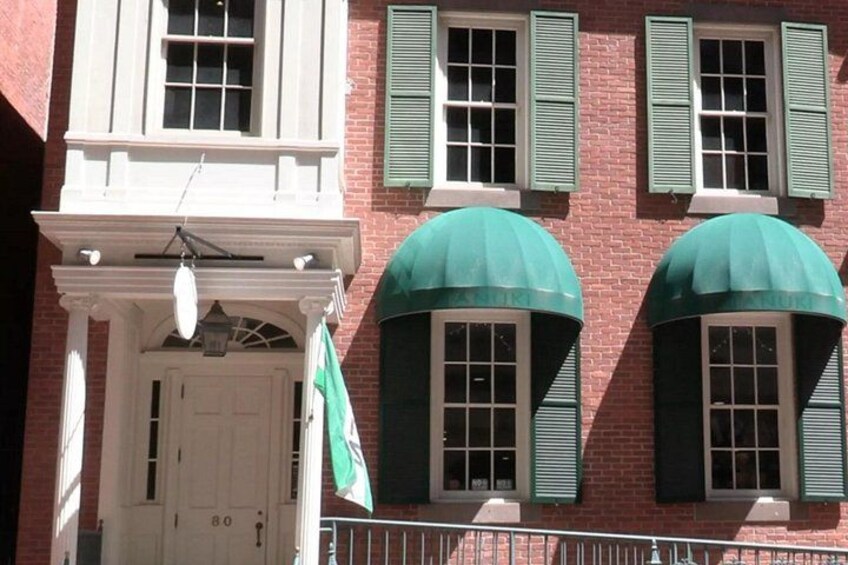 A red brick building with white trim, green shutters, and a white door. 3