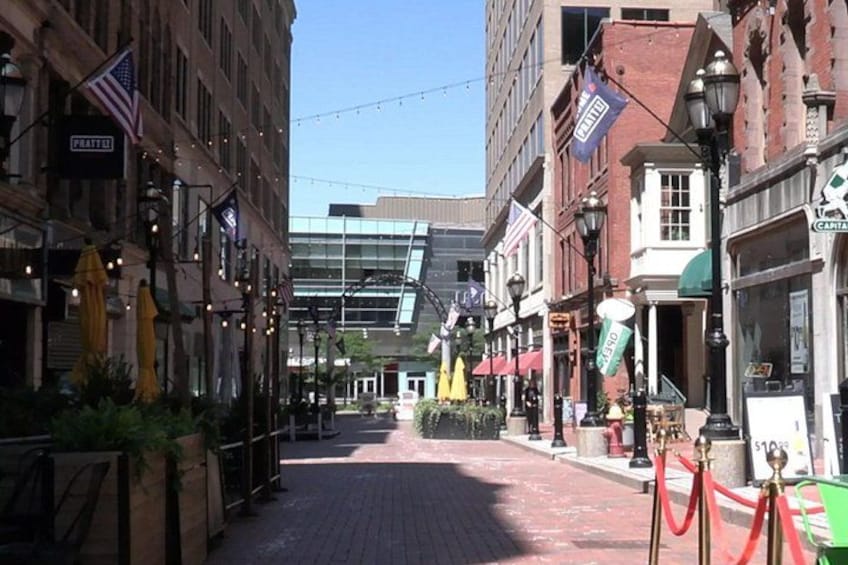 A street lined with buildings, some with flags, and a red carpet leading to a building entrance. 4
