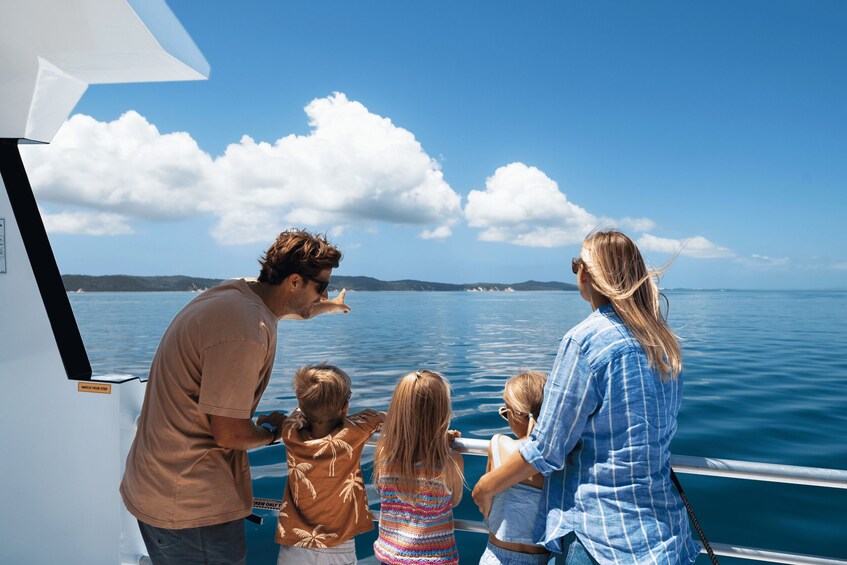 A family on a boat with a clear view of the water and distant land. 3