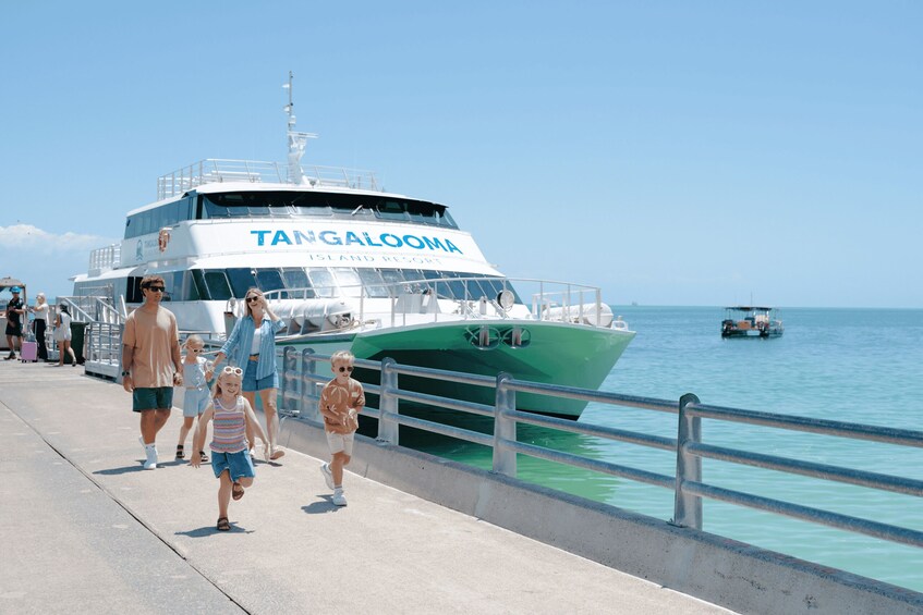 A ferry named TANGALOOMA docked at a pier with people walking along the boardwalk. 2