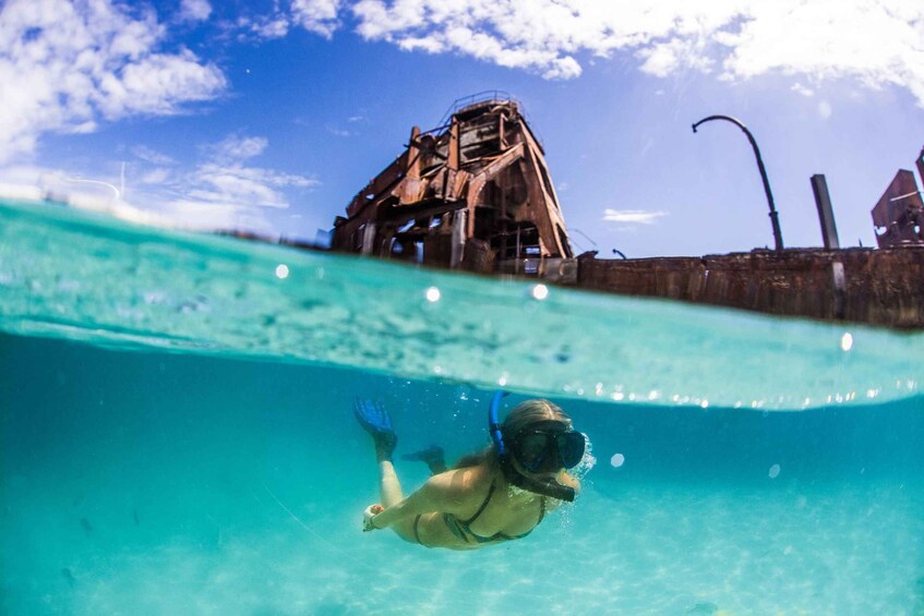 A person snorkeling underwater with a rusty structure in the background. 1