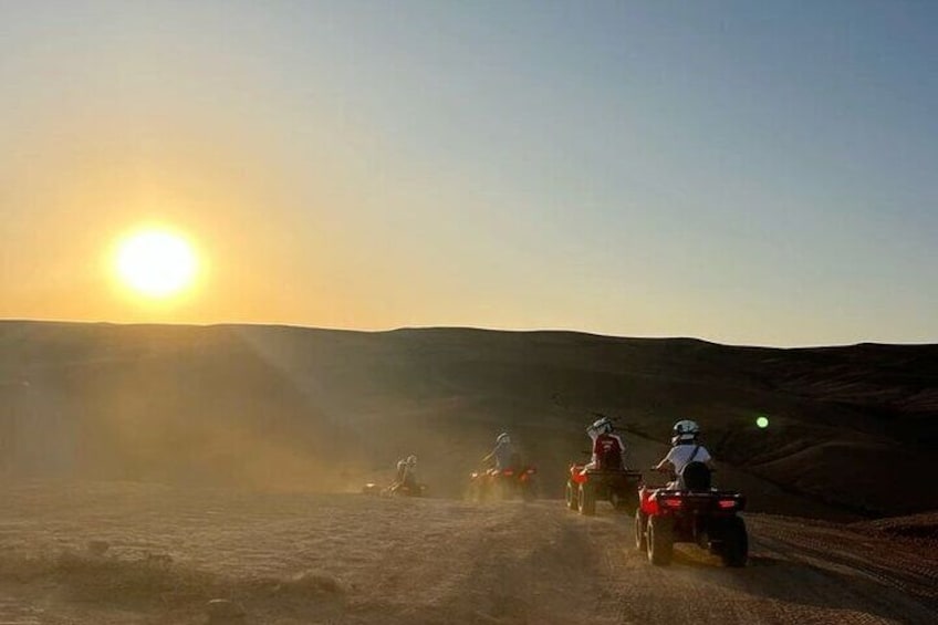 Un groupe de personnes conduisant des véhicules tout-terrain sur un sentier poussiéreux au coucher du soleil. 3