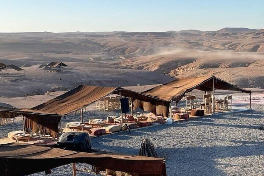 Un terrain de camping aménagé dans le désert, avec des tentes et des tables installées sur une surface de gravier. 4