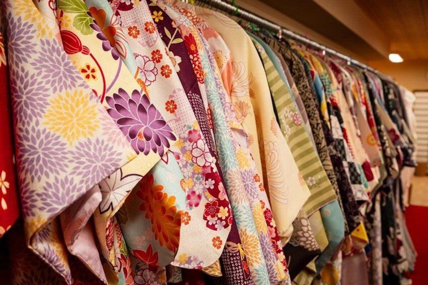A variety of colorful fabrics with floral patterns hanging on a rack. 3