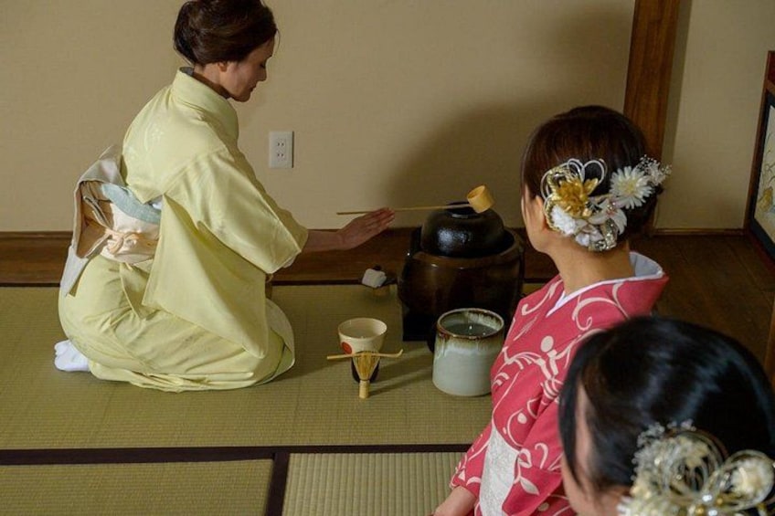Two individuals in traditional Japanese attire performing a tea ceremony. 2