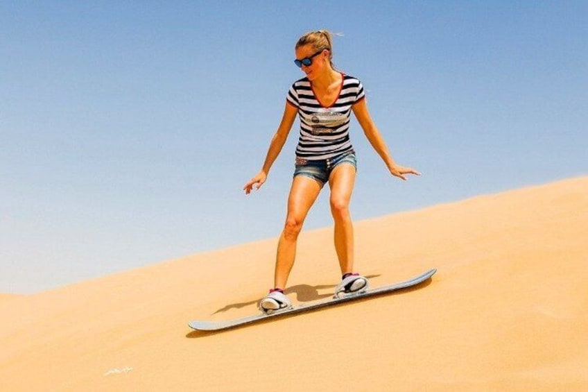 A person surfing on a board in a desert. 2