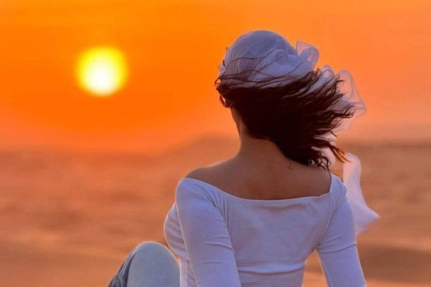 A person sitting on a beach with the sun setting in the background. 3