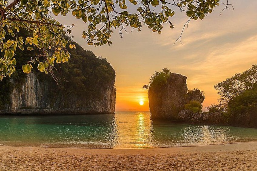 A beach with clear turquoise water, a sunset, and rocky cliffs. 3