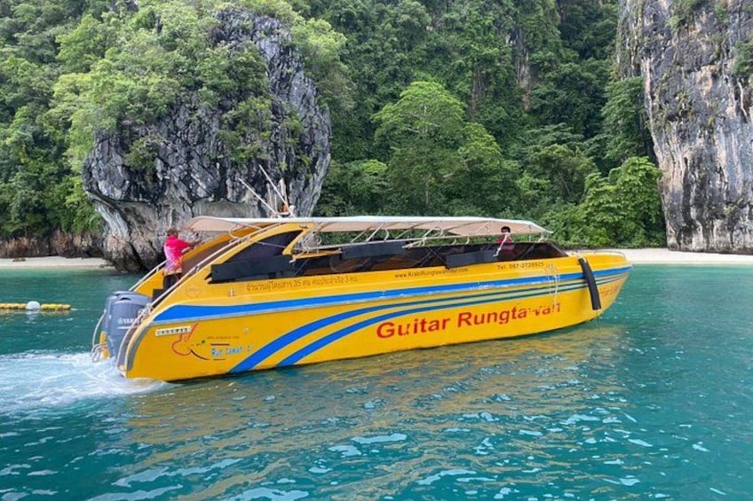 A yellow and blue boat named 'Guitar Rungta' on a turquoise sea with a rocky island in the background. 4