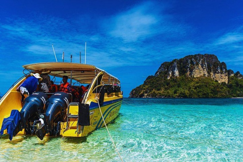 A boat with passengers, clear turquoise water, and a rocky island in the background. 5