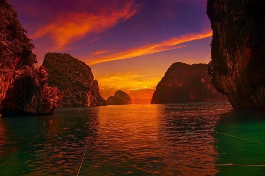 A sunset over a body of water with rock formations. 2