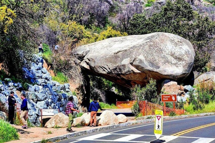 A large rock formation, a road with a pedestrian crossing, and a sign indicating a viewpoint. 3