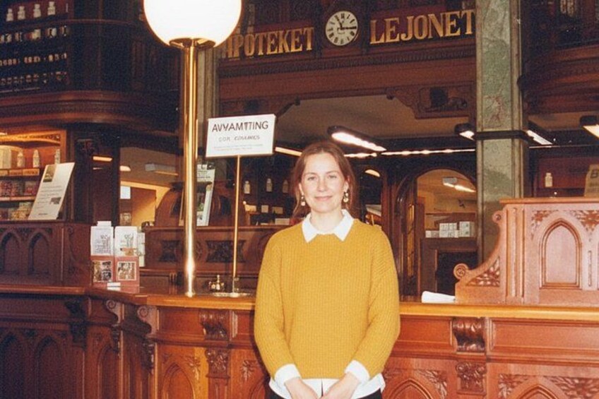 A person standing in a warmly lit, ornately decorated interior with wooden furniture and a sign reading 'AVVAMTING.' 3