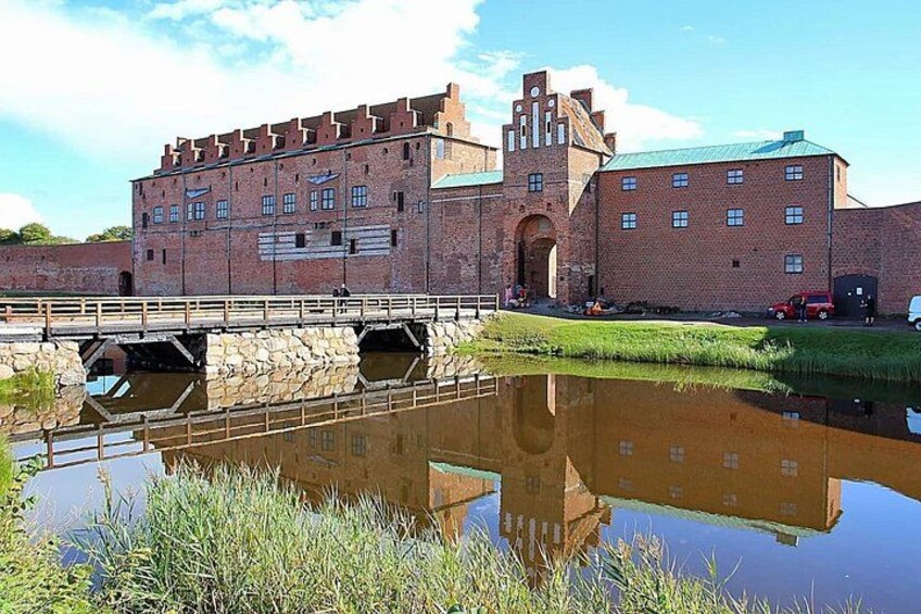 A historic brick building with a moat and a bridge. 2