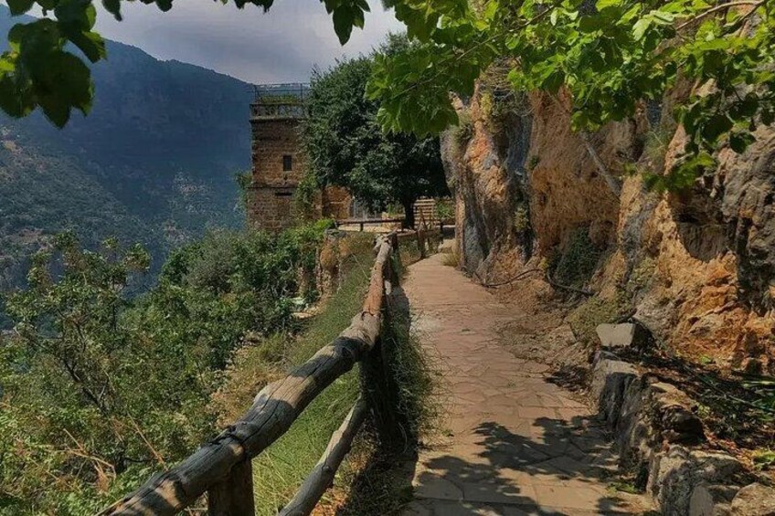 A stone pathway leading to a tower amidst a mountainous landscape. 2