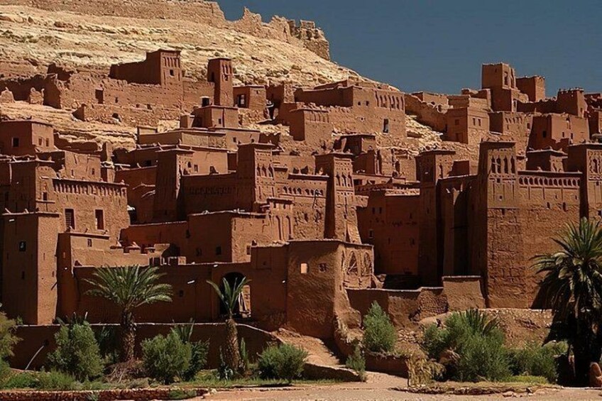Un village traditionnel construit en briques de terre, avec des bâtiments à étages et des palmiers. 3
