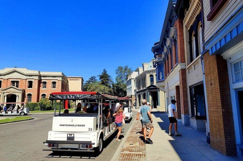 A white tour bus with passengers, parked on a street lined with historic buildings. 4