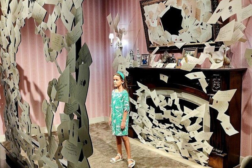 A room with a fireplace, a woman in a green dress, and numerous papers scattered around. 3